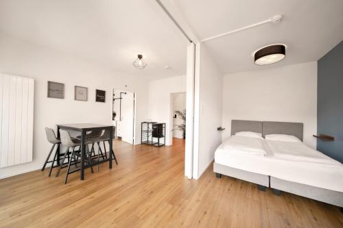 a white bedroom with a bed and a table at Hotel by Hyve Basel in Basel