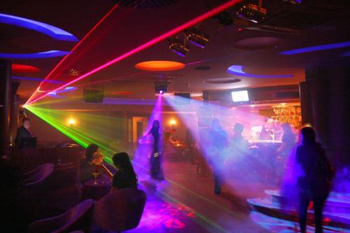 a group of people dancing in a room with lasers at Hotel Prezydent Krynica Zdrój in Krynica Zdrój