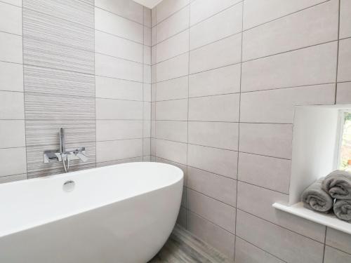 a white bathroom with a tub and a sink at Nant Coed Barn in Abergele