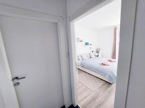a white bedroom with a bed and a window at Apartments Sv.Jakov in Dubrovnik