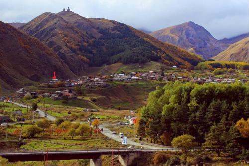 a small town in a valley with mountains at Red Stone Guest House in Stepantsminda