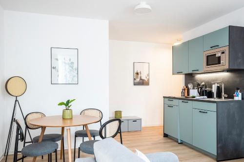 a kitchen with blue cabinets and a table and chairs at limehome Villach Hauptplatz in Villach
