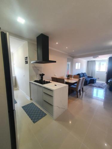 een keuken en een woonkamer met een fornuis en een tafel bij Apartamento de Luxo com Piscina em Bombinhas in Bombinhas