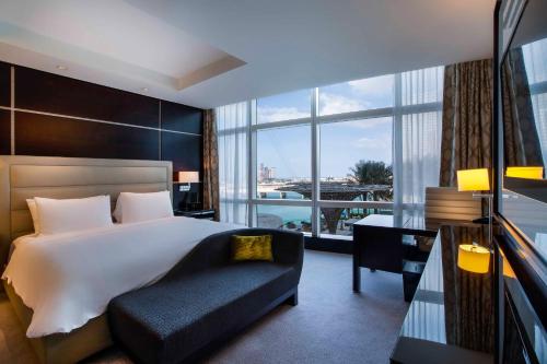 a bedroom with a bed and a couch and a window at Rosewood Abu Dhabi in Abu Dhabi