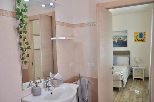 een badkamer met een wastafel, een spiegel en een bed bij B&B Rosa dei Venti in Santa Teresa Gallura