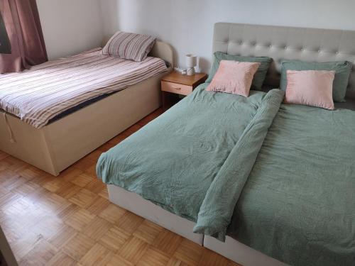 a bedroom with two beds with green sheets and pink pillows at Guesthouse Suzy in Pula