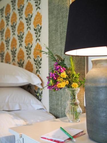 a vase of flowers on a table next to a bed at St Michael Liston Suite in Corfu