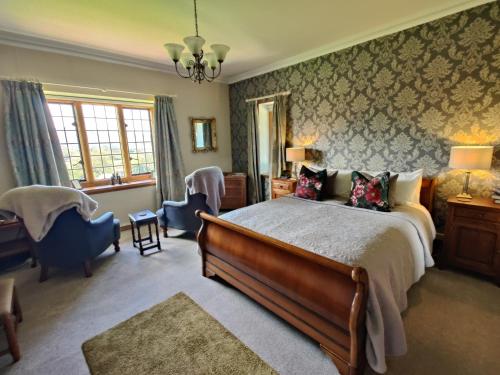 Luxury Bed And Breakfast at Bossington Hall in Exmoor, Somerset في بورلوك: غرفة نوم بسرير كبير وكرسي
