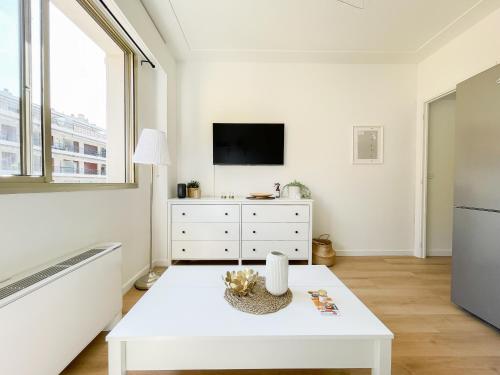 - un salon blanc avec une télévision et une table basse blanche dans l'établissement Studio bord de mer 3, à Menton