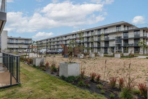an apartment building with a garden in front of it at Wellness Resort & SPA Dziwnów Apartments with Parking by Noclegi Renters in Dziwnów
