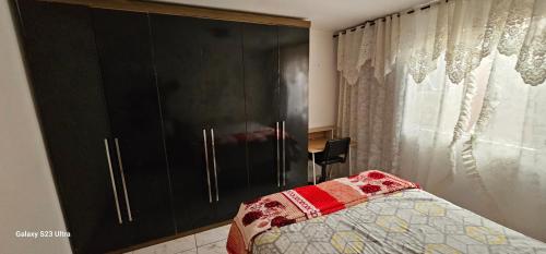 a bedroom with a bed and a black cabinet at Hostel AJBJ Turismo in Curitiba