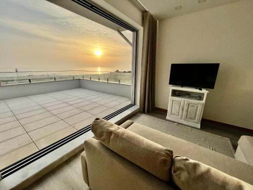 a living room with a couch and a large window at Breathtaking ocean front studio in Povoa de Varzim in Póvoa de Varzim