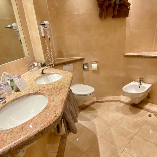 a bathroom with two sinks and a toilet in it at Treschers Schwarzwald Hotel in Titisee-Neustadt