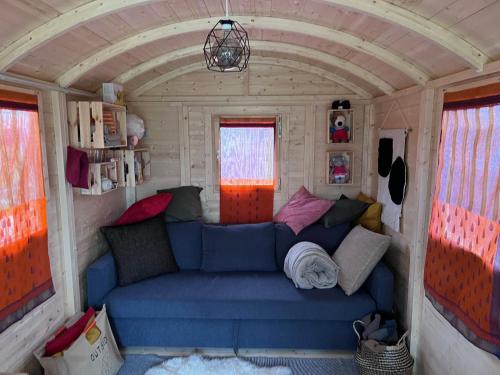 una sala de estar en una casa pequeña con un sofá azul en Ontwaken tussen de paarden, en Helen-Bos