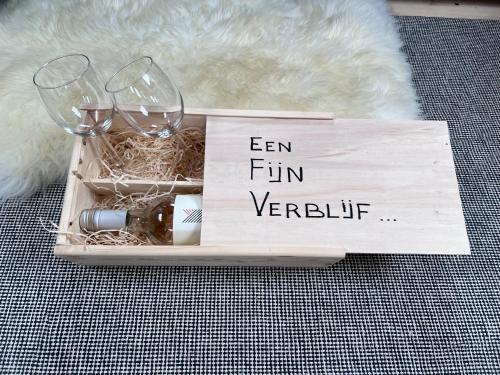 a wooden crate with two wine glasses and a sign at Ontwaken tussen de paarden in Helen-Bos