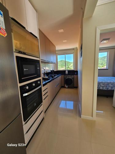 a kitchen with a sink and a stove top oven at Cobertura em Bombinhas - Piscina - Luxo - Alto Padrão in Bombinhas