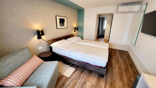 a small room with a bed and a couch at Hotel Pestalozzi Lugano in Lugano