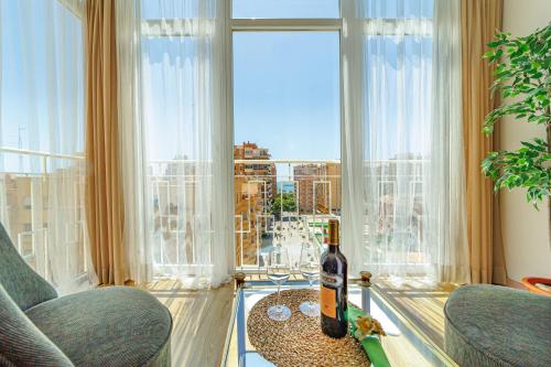 Habitación con una botella de vino en una mesa frente a una ventana en Perla de Malagueta, en Málaga