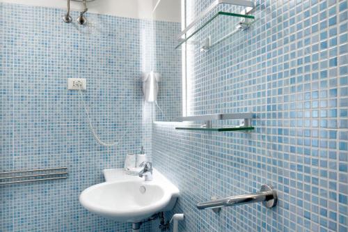 a blue tiled bathroom with a sink and a shower at Edda's apartment in Altare