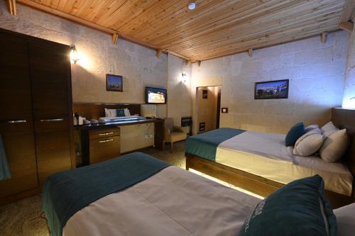 a hotel room with two beds and a desk at Aden Hotel Cappadocia in Uçhisar