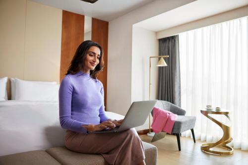a woman sitting on a couch with a laptop at Hyatt Regency Trivandrum in Trivandrum
