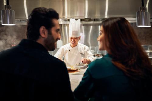 a man and a woman standing in a kitchen with a chef at Hyatt Regency Trivandrum in Trivandrum