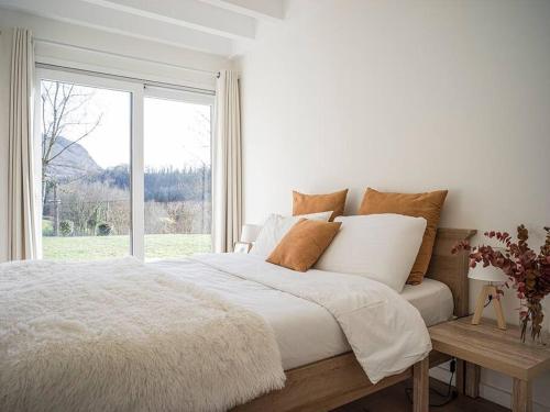 a white bedroom with a large bed and a window at Venez Chez Vous - Le Cocon du Parmelan in Nâves-Parmelan