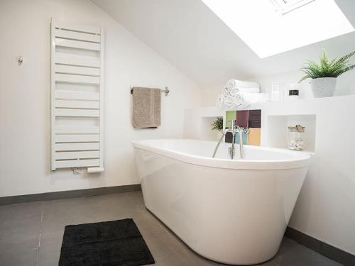 baño con bañera blanca y ventana en Venez Chez Vous - Le Cocon du Parmelan en Nâves-Parmelan
