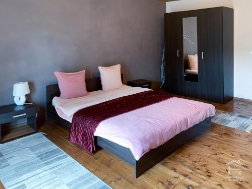 a bedroom with a large bed with pink pillows at Apartamentai Biržuose, double bedroom and single bedroom Apartments in Biržai