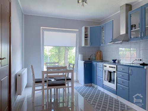 a kitchen with blue cabinets and a table and a dining room at Apartamentai Biržuose, double bedroom and single bedroom Apartments in Biržai