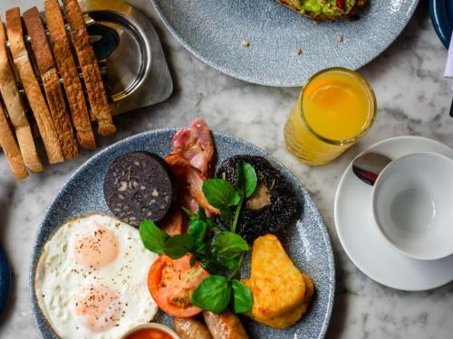 a table with two plates of breakfast food and a glass of orange juice at Apex City of Edinburgh Hotel in Edinburgh