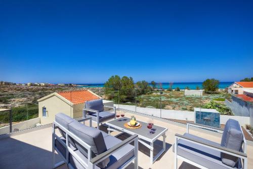 uma varanda com cadeiras e uma mesa e vista para o oceano em Villa Makisland With Sea View em Stavros