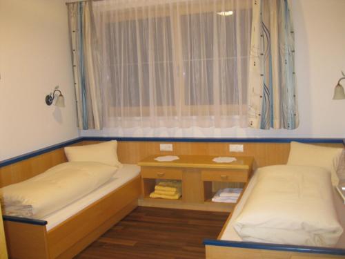 トゥクスにあるApartment Gittiのベッド2台と窓が備わる小さな客室です。