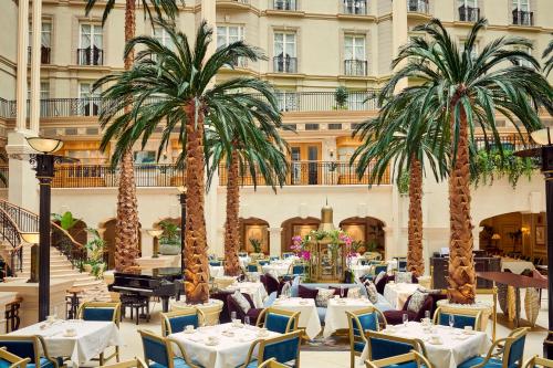a restaurant with tables and palm trees in front of a building at The Landmark London in London