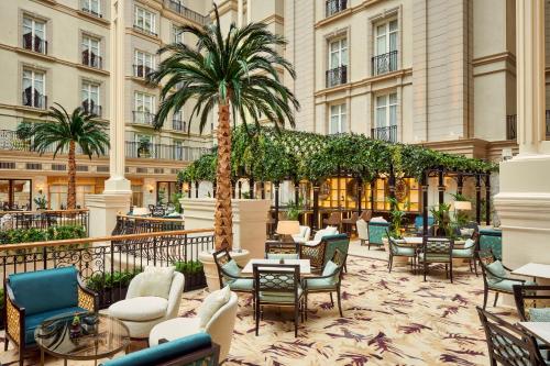 a hotel lobby with chairs and tables and a palm tree at The Landmark London in London