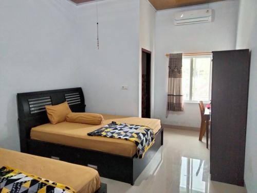 a bedroom with two beds and a table and a window at Domen homestay syariah krui 64 in Krui
