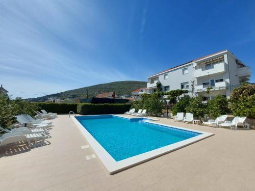 a swimming pool with chairs and a building at Apartments Zulim in Trogir
