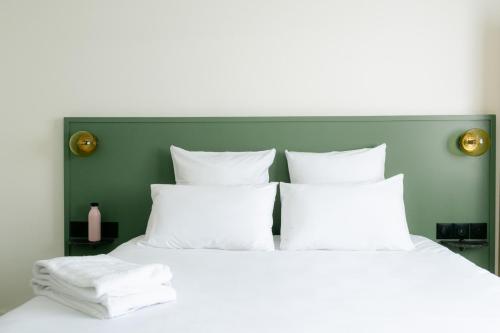 - un lit avec des oreillers blancs et une tête de lit verte dans l'établissement Le Lieu Dit, à Nantes