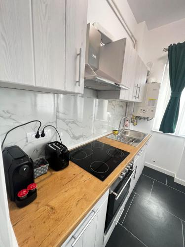 a kitchen with white cabinets and a wooden counter top at Cozy Aparthotel - Central City Suceava in Suceava