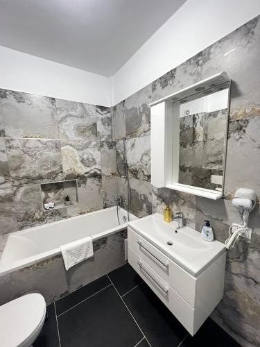 a bathroom with a sink and a tub and a toilet at Cozy Aparthotel - Central City Suceava in Suceava