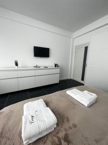 a white room with a tv and two white towels at Cozy Aparthotel - Central City Suceava in Suceava