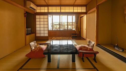 um quarto com uma mesa e duas cadeiras e uma janela em Fujiya em Kaga