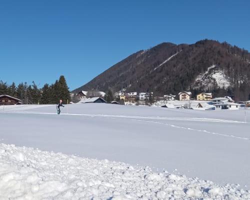 a person is walking on a snow covered field at Unterwöhrlehen in Faistenau