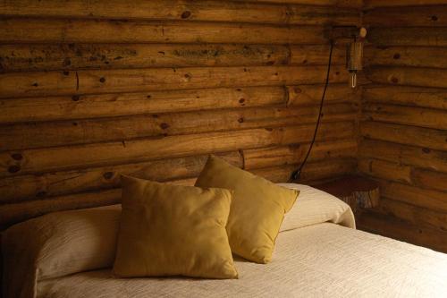 1 dormitorio con paredes de madera y 1 cama con almohadas en Cabañas El Sosiego en Azul