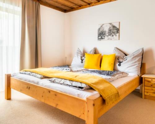 a bedroom with a wooden bed with yellow pillows at Unterwöhrlehen in Faistenau