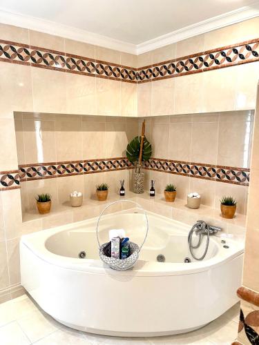 a white tub in a bathroom with plants at Magellan House in Vilamoura
