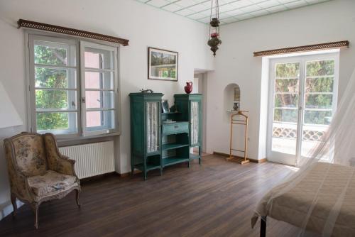 a bedroom with a bed and a chair and windows at The Villa Averoff in Kírinthos