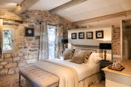 メネルブにあるLa Bastide de Marie, Maisons et Hôtels Sibuetの石壁のベッドルーム1室(ベッド1台付)