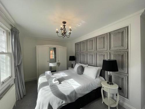 Un dormitorio con una gran cama blanca y una lámpara de araña. en Castle View House en Lincolnshire