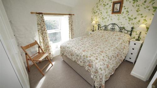 een slaapkamer met een bed, een raam en een stoel bij Frog Lane Cottages in Llanmadoc